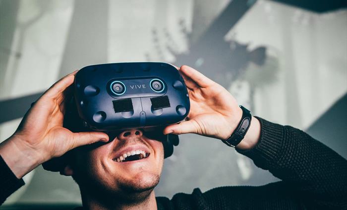 young man, smiling, wearing virtual reality headset